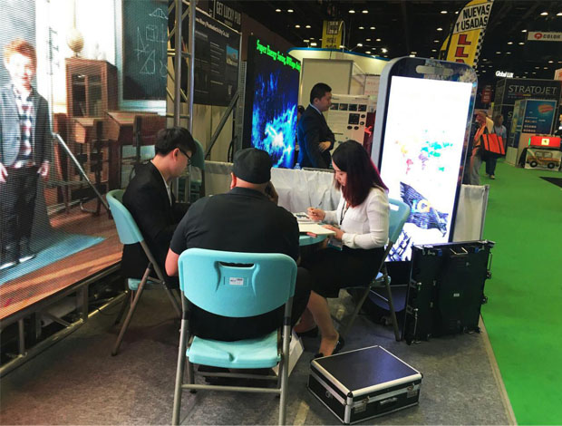 奥兰多橘城会展中心钱柜QG777展位现场，外贸部经理黄勇强和何巧玲与意向客户在交谈中